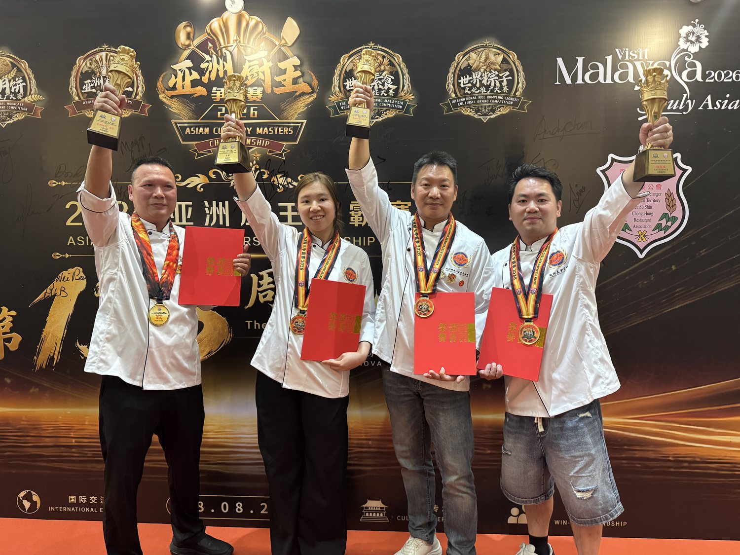 Vier chefs houden hun gouden bekers en oorkondes omhoog voor de backdrop van de Asian Culinary Masters Championship 2026